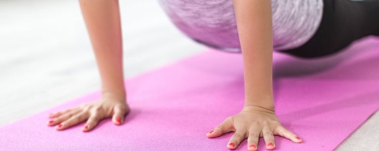 Frau in Plank-Position auf pinker Yogamatte, ideal für Fitness- und Ernährungsinhalte.