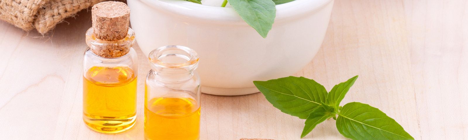 1711-gezondere-vetopslag-1600x480_1 Kleine Glasflaschen mit goldenem Öl und frischen grünen Blättern, ideal für Fitness-Ernährung.