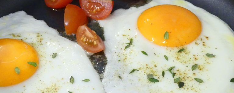 Zwei Spiegeleier mit Tomaten, verfeinert mit Kräutern, perfekt für Ihr Fitness-Frühstück.