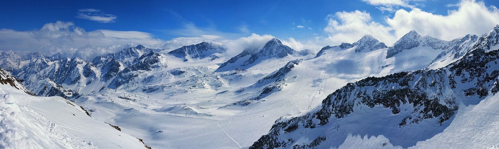 BF-Skien-1600×480 Schneebedeckte Berggipfel und Skipisten, ideal für aktiven Wintersport und Fitness.