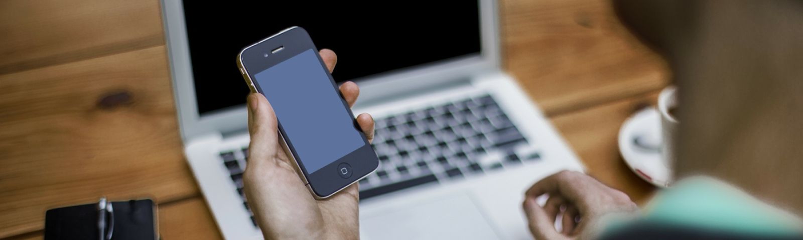 Person hält Smartphone vor Laptop. Fitness-Ernährungs-Firma.