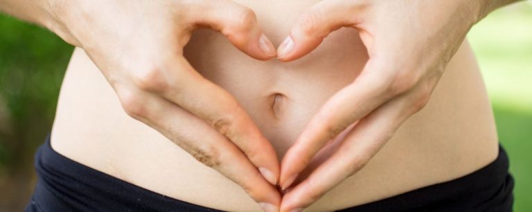 Hände bilden ein Herz über dem Bauch. Fitnesstipps und gesunde Ernährung für ein Herz-Kreislauf-System.