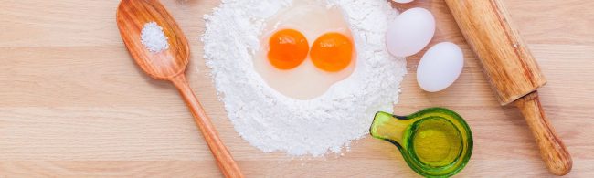 Zutaten für Fitness-Backen: Mehl, Eier, Öl und Salz auf Holzbrett.