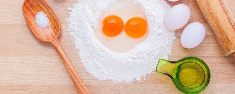 Zutaten für Fitness-Backen: Mehl, Eier, Öl und Salz auf Holzbrett.