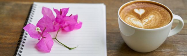 Latte Art Kaffee und pinke Blume auf Notizbuch für Fitness-Ernährung