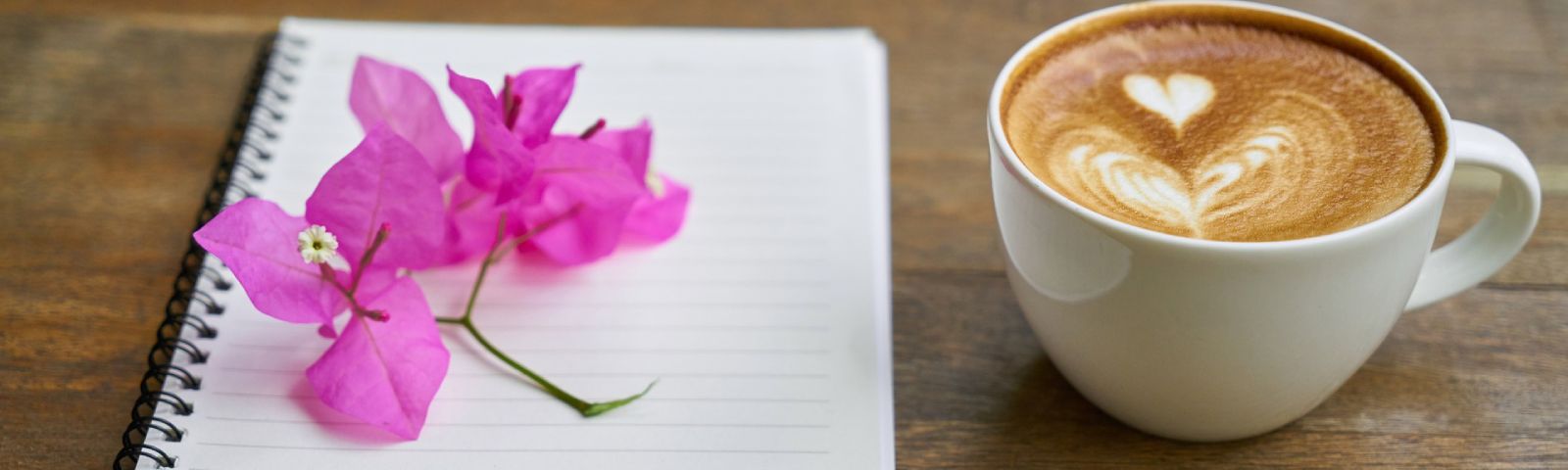 Latte Art Kaffee und pinke Blume auf Notizbuch für Fitness-Ernährung