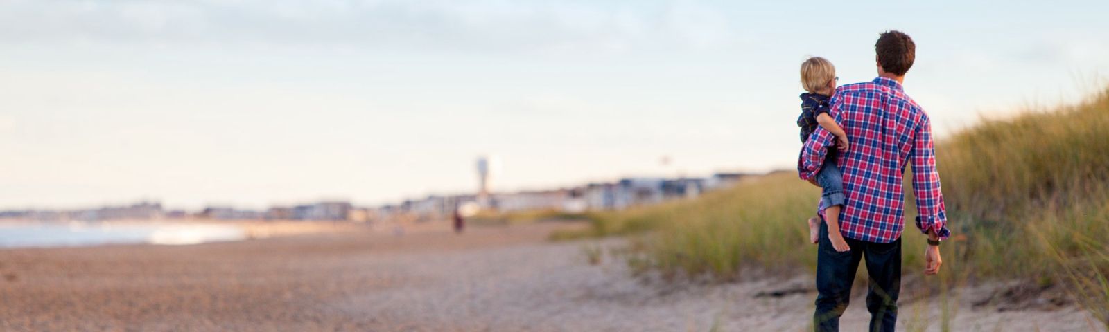 Vater trägt Sohn am Strand, gesunde Ernährung für Familien.