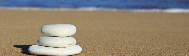 Balance: Gestapelte Steine am Strand, die Ruhe und Konzentration für Ihr Fitness-Training symbolisieren.