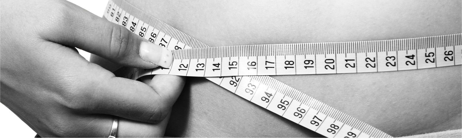 buikvet-maart-groot_1 Eine Hand misst die Taille mit einem Maßband, was Gewichtsverlust und Fitnessziele symbolisiert.