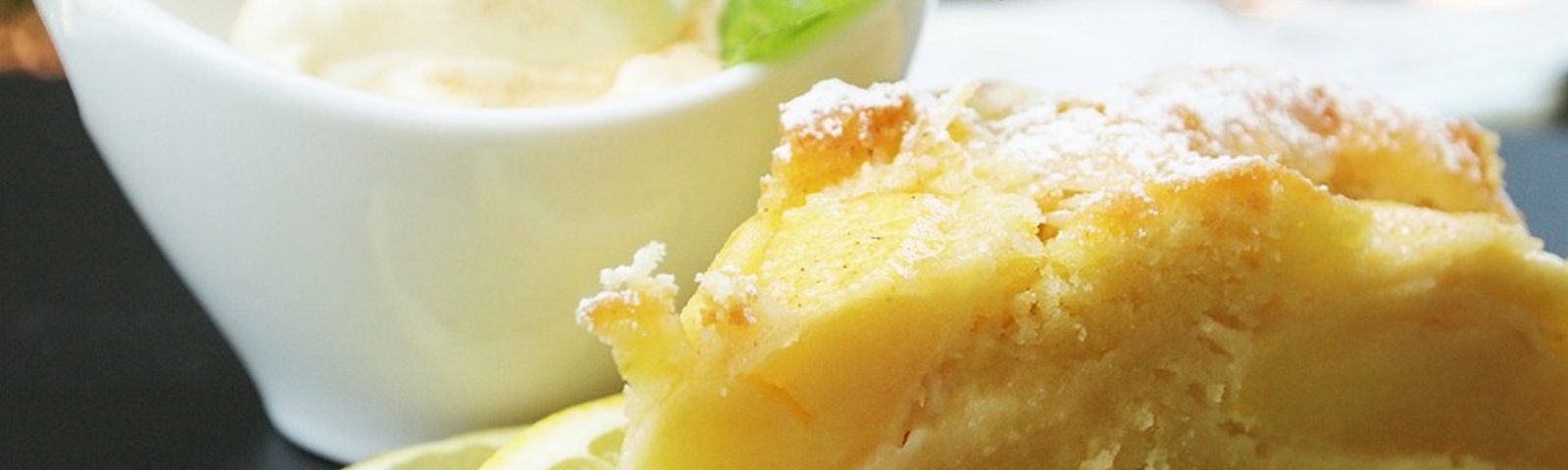 fotogroot-2 Ein Stück Zitronenkuchen bestäubt mit Puderzucker, serviert mit Eis und einer Zitronenscheibe.