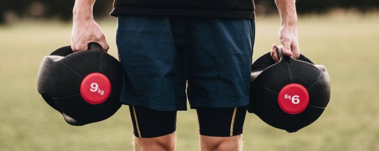 Ein Mann mit Trainingsgewichten im Freien. Fitness und Ernährung im Fokus.