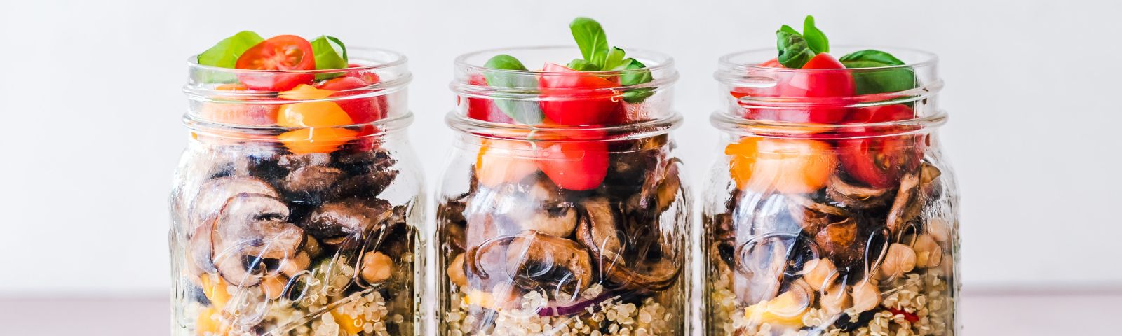 Drei gesunde Mahlzeiten im Glas: Quinoa, Pilze, Tomaten und Basilikum – perfekt für Fitness-Fans.