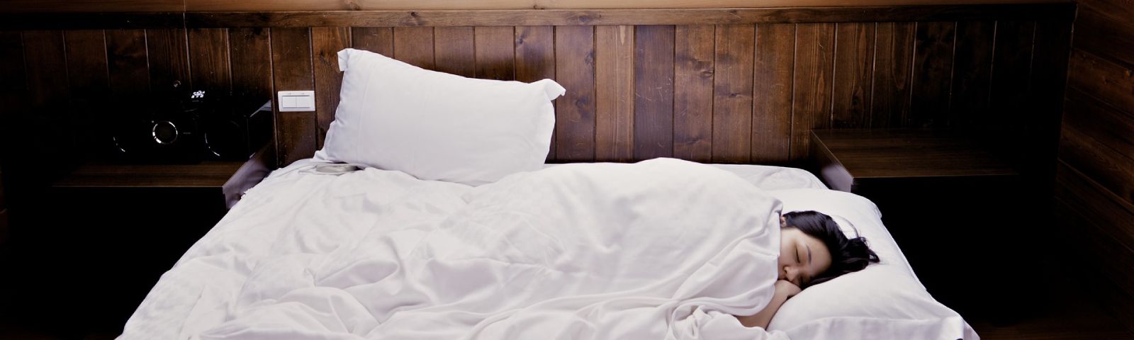 moeite-met-opstaan-1600×480 Eine Frau schläft im Bett, was auf eine gesunde Erholung für Fitness und Ernährung hinweist.