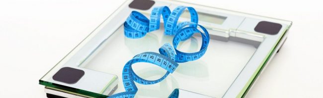 Personenwaage mit Maßband, Symbol für Gewichtsverlust und gesunde Ernährung.