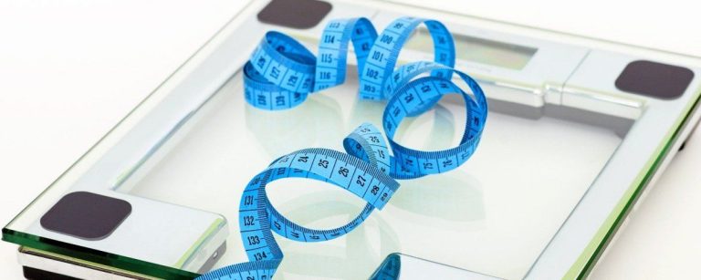 Personenwaage mit Maßband, Symbol für Gewichtsverlust und gesunde Ernährung.