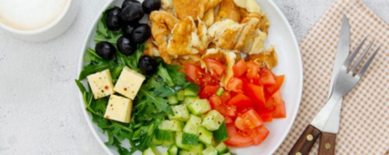 Fitness-Frühstück: Rührei, Salat, Tomaten, Gurke, Käse und Oliven. Gesunde Mahlzeit.