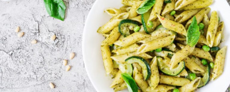 Gesunde Penne-Pasta mit Zucchini und Erbsen in Pesto, ein proteinreiches Gericht für Sportler.