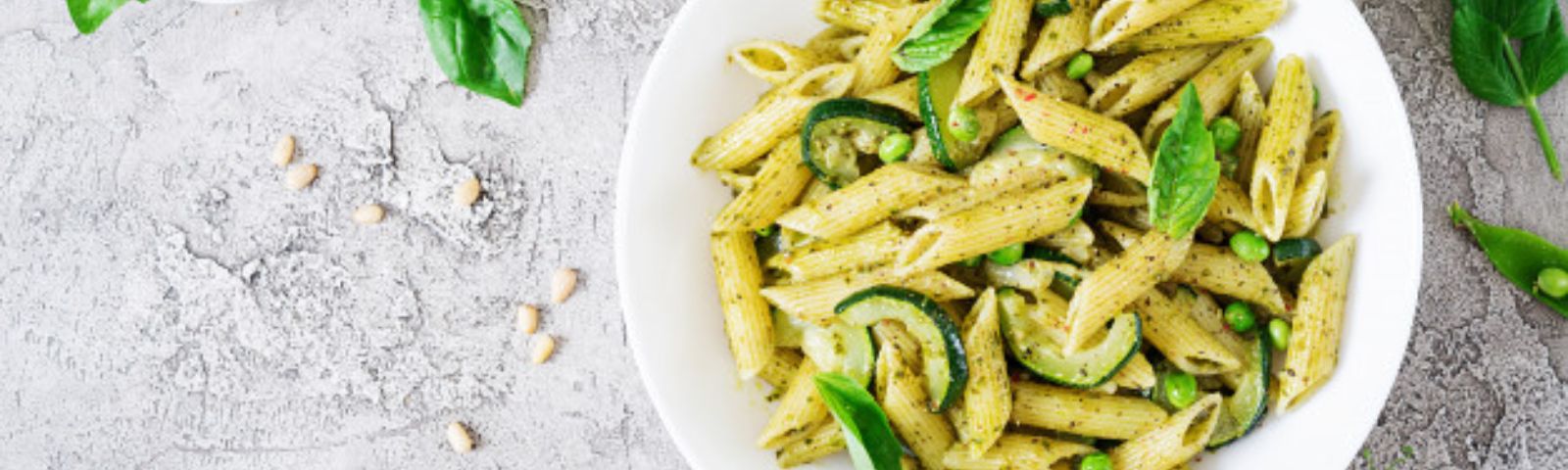 Gesunde Penne-Pasta mit Zucchini und Erbsen in Pesto, ein proteinreiches Gericht für Sportler.