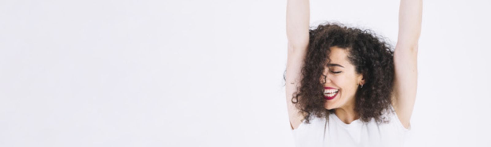 verheugen 1600x 480 Frau mit Locken und roten Lippen, die lacht, vor weißem Hintergrund für Fitness-Ernährung.