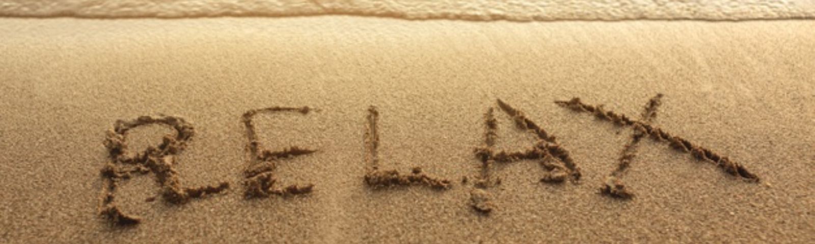 relaxt vertrek 1600×480 Wort "RELAX" in Sand geschrieben am Strand - Fitness und gesunde Ernährung für dein Wohlbefinden.