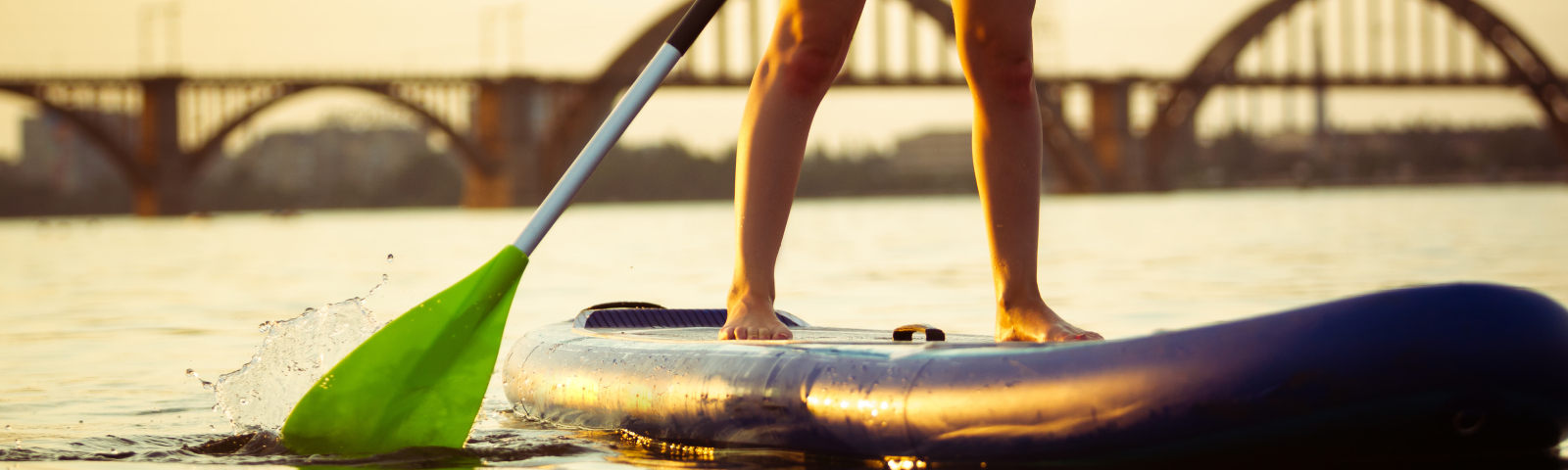 Eine Frau steht auf einem SUP-Board im Wasser und paddelt.