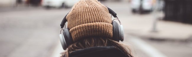 Frau mit Kopfhörern und Beanie hört Musik beim Sporttraining.