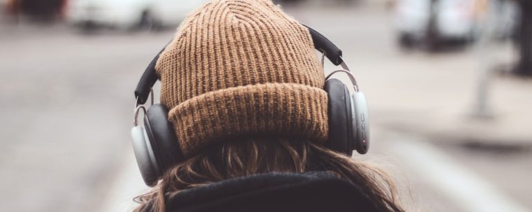 Frau mit Kopfhörern und Beanie hört Musik beim Sporttraining.
