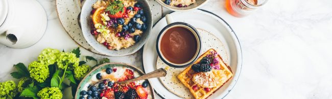 gezond ontbijten 1600×480 Gesunde Frühstücksschüssel mit Obst, Haferflocken, Beeren, Waffeln und Kaffee.