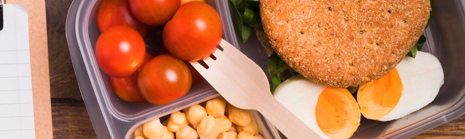 Gesunde Mahlzeit: Tomaten, Kichererbsen, Ei und Vollkornbrot im Bento-Behälter.