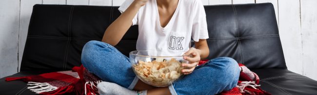 troosteten 1600×480 Person is eating chips on a couch.