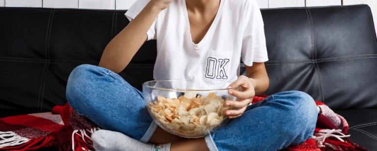 Person is eating chips on a couch.
