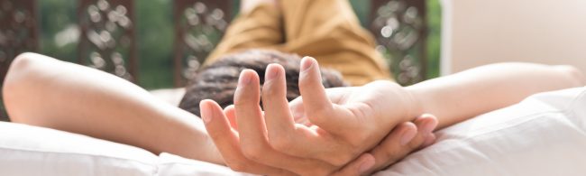 Entspannter Mensch mit Händen hinter dem Kopf auf weißem Kissen, ein Symbol für Erholung nach dem Training.