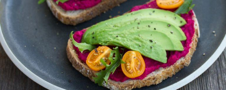 Vegane Avocado-Toast mit Rote-Bete-Aufstrich und Tomaten für gesunde Ernährung.