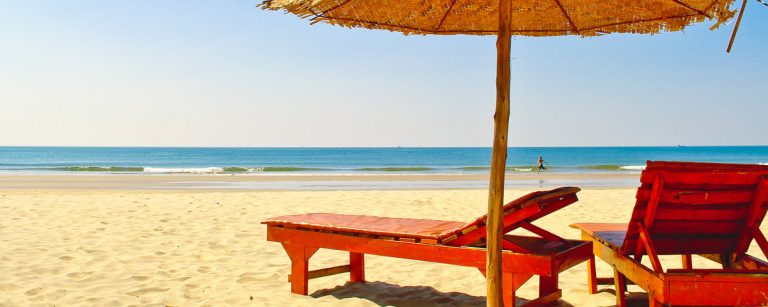 Rote Liegen am Strand unter Sonnenschirm, gesunde Erholung für dein Training.