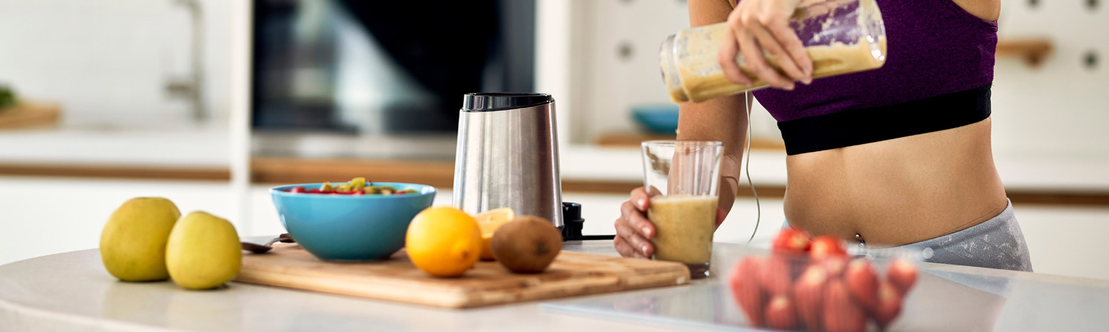 Frau macht Smoothie in der Küche, gesunde Ernährung für Fitness.