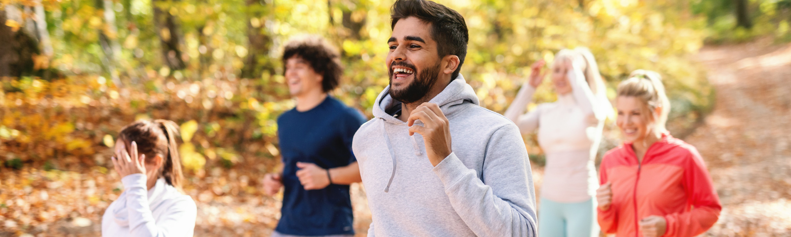 powerwalking Lächelnde Menschen beim Joggen im Herbstwald, fit und gesund dank gesunder Ernährung.