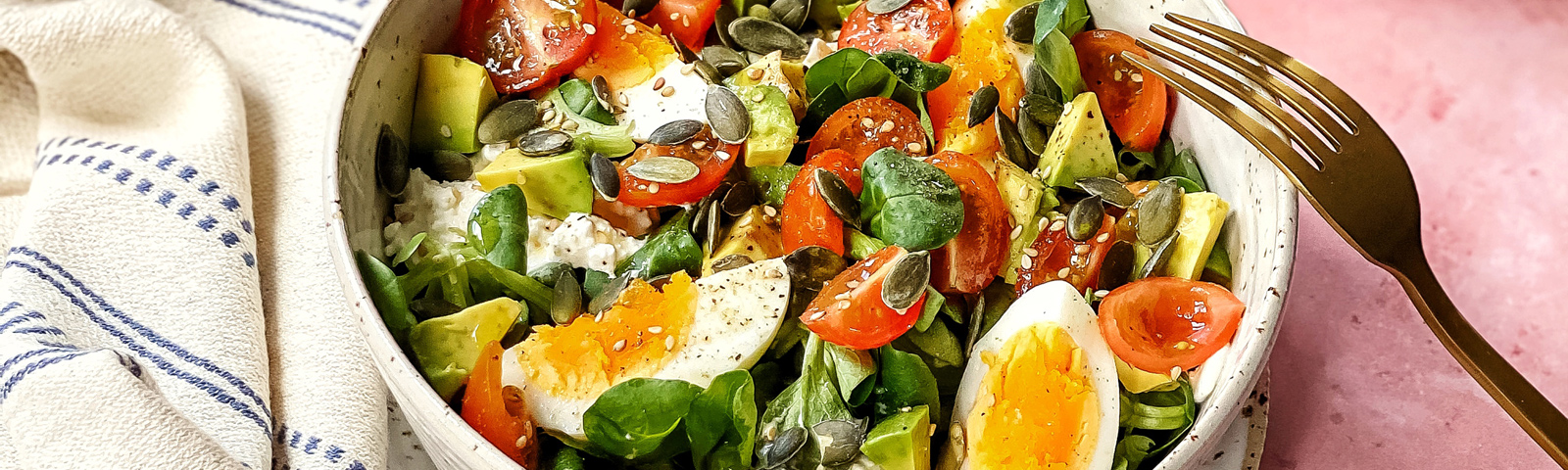 Gesunder Fitness-Salat mit Ei, Avocado, Tomaten und Kernen.