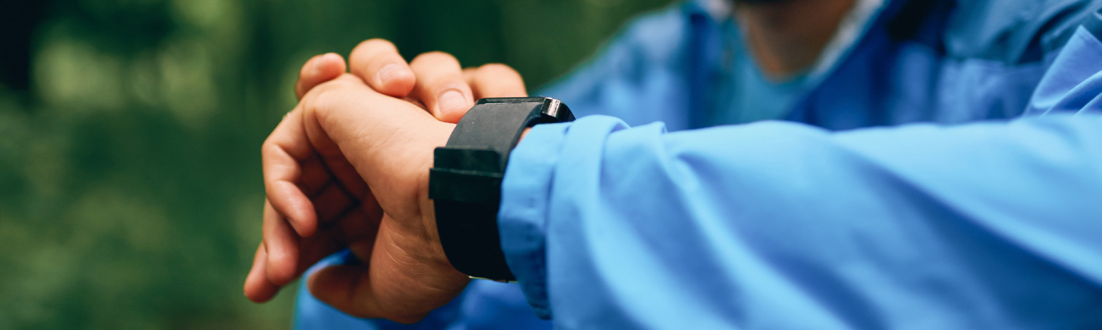 Person prüft Smartwatch mit blauem Trainingsanzug, Fokus auf Fitness.