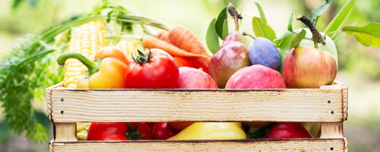 Assorted organic produce like strawberries, spinach, peppers and kale beside conventional options such as avocados and onions, illustrating what to buy organic.