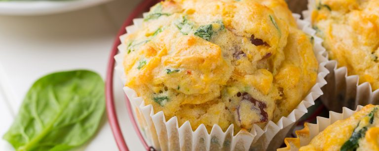 Savory gluten-free veggie muffins with zucchini and carrot cooling on a wire rack, rustic kitchen setting.