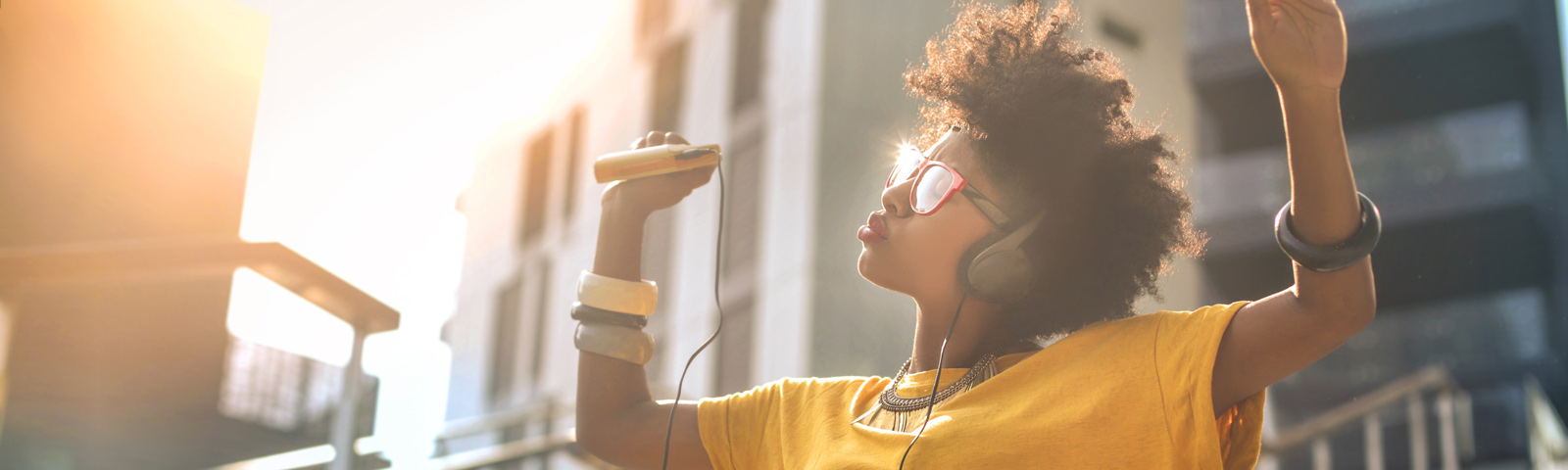Person relaxing with headphones in a cozy room at dusk, soft warm lighting and a calm playlist on a phone screen.