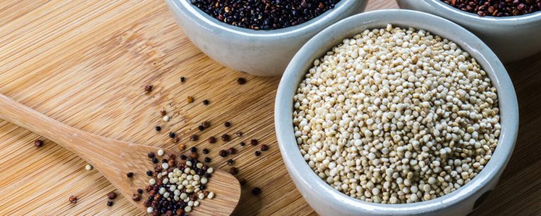 Close-up of cooked white, red and black quinoa in bowls, highlighting the grain-like seeds and their texture.