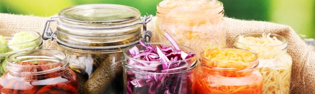 gefermenteerde_voedingsmiddelen Glasbehälter mit eingelegtem Gemüse und Obst. Fitnessfreundliche, gesunde Lebensmittel.