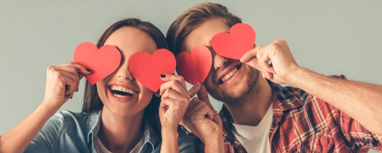 A cozy romantic dinner setup with candles, flowers, elegant napkins and soft lighting.