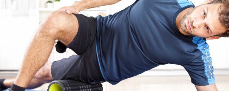 Man performing side-lying foam rolling on the outer thigh to release fascia