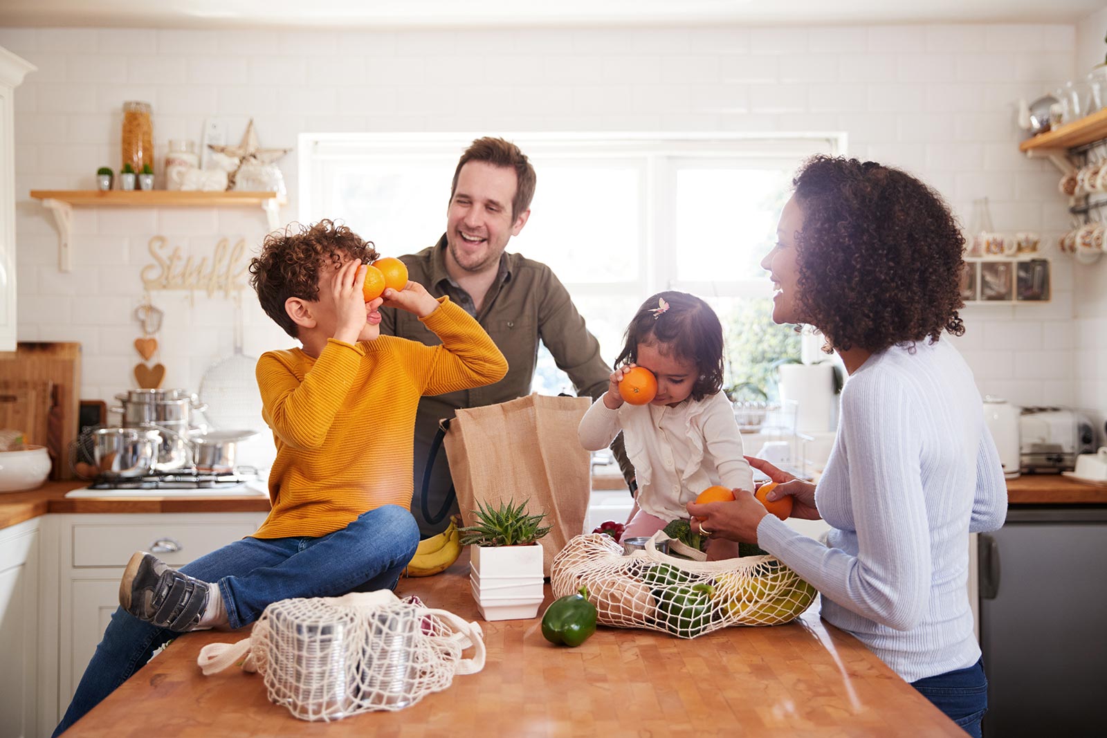 Familie genießt gesunde Ernährung: Kinder spielen mit frischem Obst & Gemüse. Vitamine für Fitness und Wohlbefinden in der Küche.