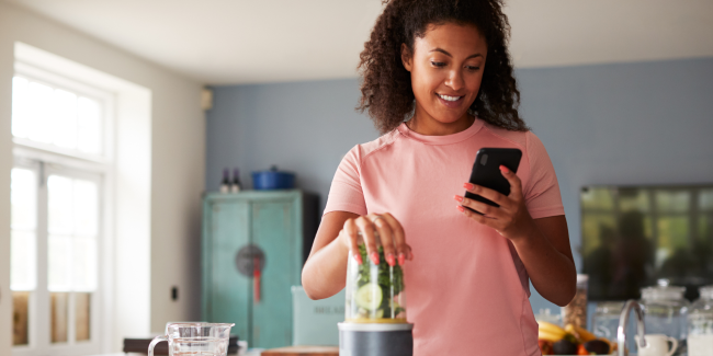 Woman tracking her food while making a smoothie in the kitchen