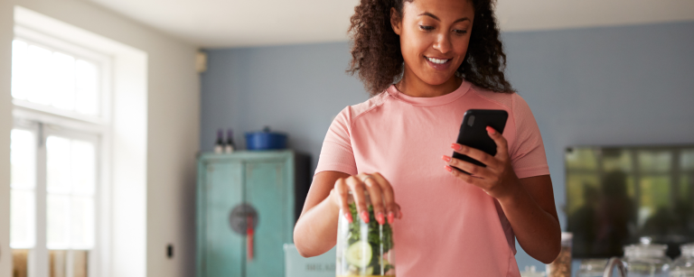 Woman tracking her food while making a smoothie in the kitchen